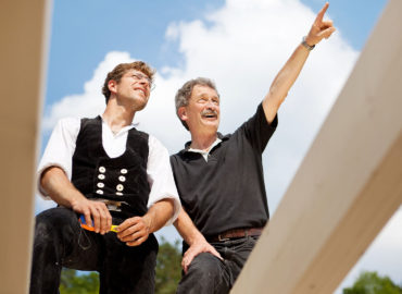 Close-up of two carpenters discussing the work on top of an unfinished roof